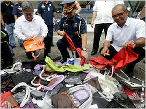 Philippine officials destroy fake handbags during the ceremonial destruction of thousands of counterfeit sunglasses, DVDs and other goods June 14, 2013, in Quezon City, Philippines.